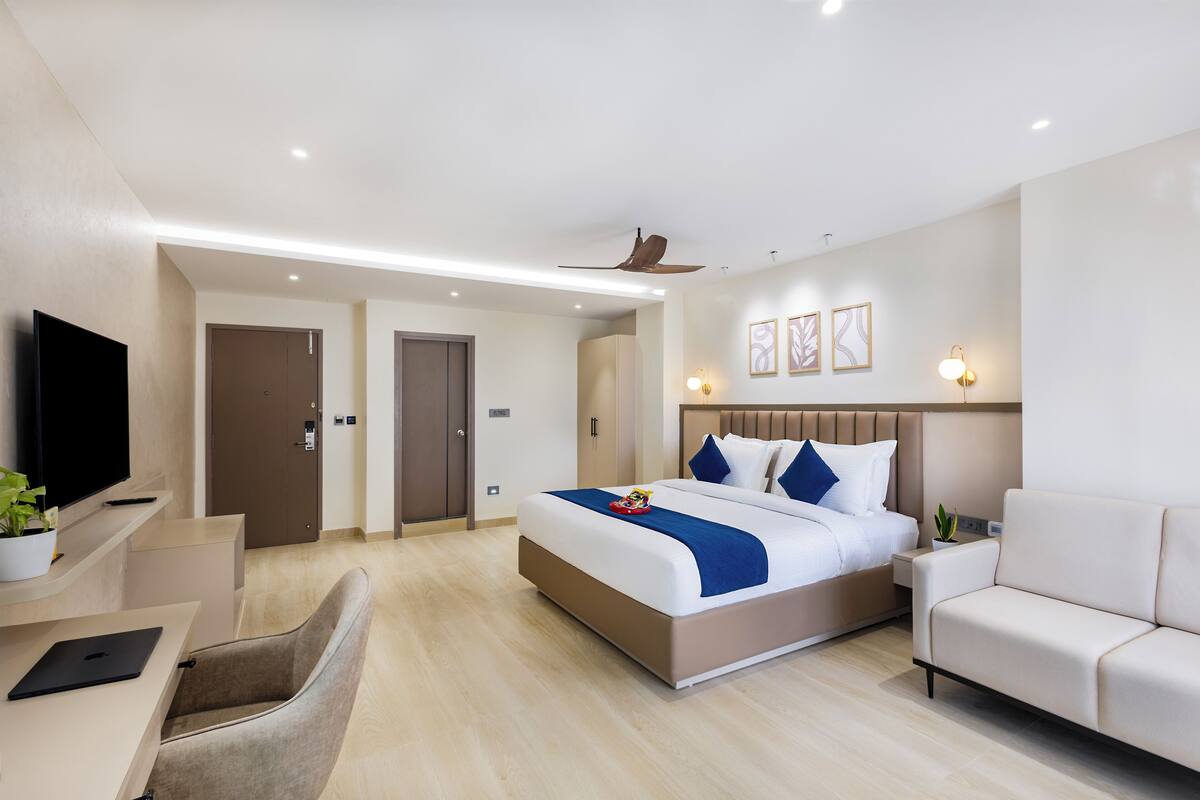Ein modernes Hotelzimmer mit einem großen Bett, einem Schreibtisch, einer Couch und einem Fernseher.
