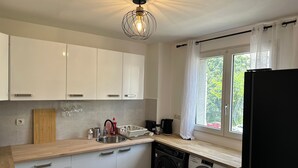 Ett modernt kök med vita skåp, en träbänkskiva, en tvättmaskin och ett fönster med gardiner.