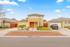 A two-story residential house with a front yard, a garage, and a car parked in the driveway. - StayAU Modern Sanctuary Mins Ct&Airport (Point Cook)