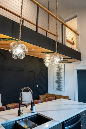 A modern kitchen with a marble countertop, a built-in sink, and a hanging light fixture. - Modern Organic Country Home w/ Hot Tub, Pet Friendly, Near USAFA (Colorado Springs)
