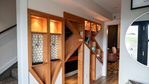 Een modern interieur met een houten trap, hexagonale schapjes en een uitzicht door een rond raam.