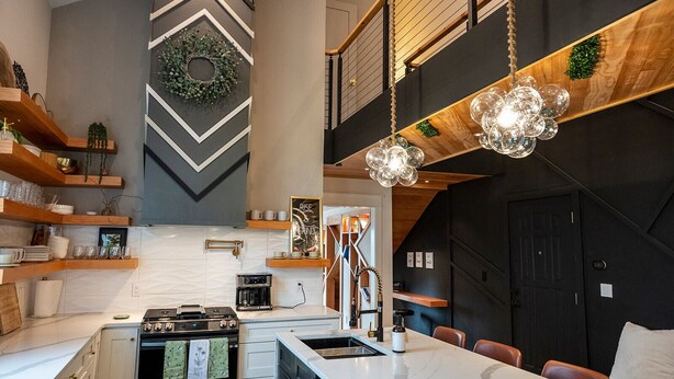 Een moderne keuken met een centraal eiland, een inbouwoven en een hangende lamp.