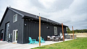 Een modern zwart gebouw met een patio, complete met buitenmeubilair en een lichtslingering.
