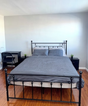 A bed with a metal frame, a desk, and two small potted plants. - Modern 3-bedroom 1 full bath apartment in wonderful south Philadelphia area. (Philadelphia)