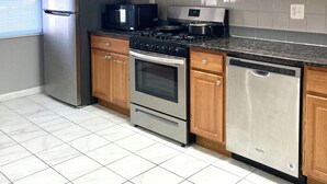 Una cocina con armarios de madera, electrodomésticos de acero inoxidable y un salpicadero de azulejos.