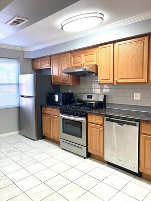 A kitchen with wooden cabinets, stainless steel appliances, and a tiled backsplash. - Modern 3-bedroom 1 full bath apartment in wonderful south Philadelphia area. (Philadelphia)