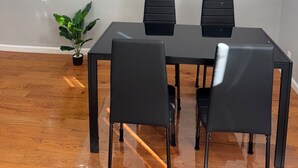 Un comedor moderno con una mesa de vidrio, sillas negras y una planta en maceta.