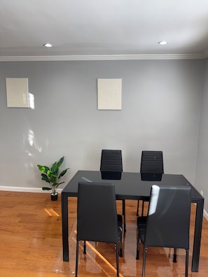 A modern dining area with a glass table, black chairs, and a potted plant. - Modern 3-bedroom 1 full bath apartment in wonderful south Philadelphia area. (Philadelphia)