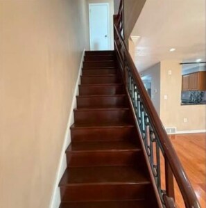 A wooden staircase with a handrail leading to a door at the top. - Modern 3-bedroom 1 full bath apartment in wonderful south Philadelphia area. (Philadelphia)
