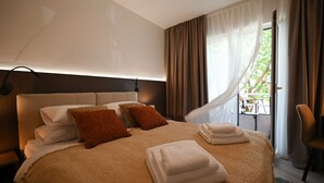 A modern hotel room with a large bed, a bedside table, a chair, and a window with curtains. - Modern and Stylish Apartment With Terrace (Rovinj)