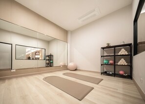 A modern room with a large mirror, exercise mats, a shelf with decorative items, and a wooden floor. - Adelphi Itsaraphap (Bangkok)