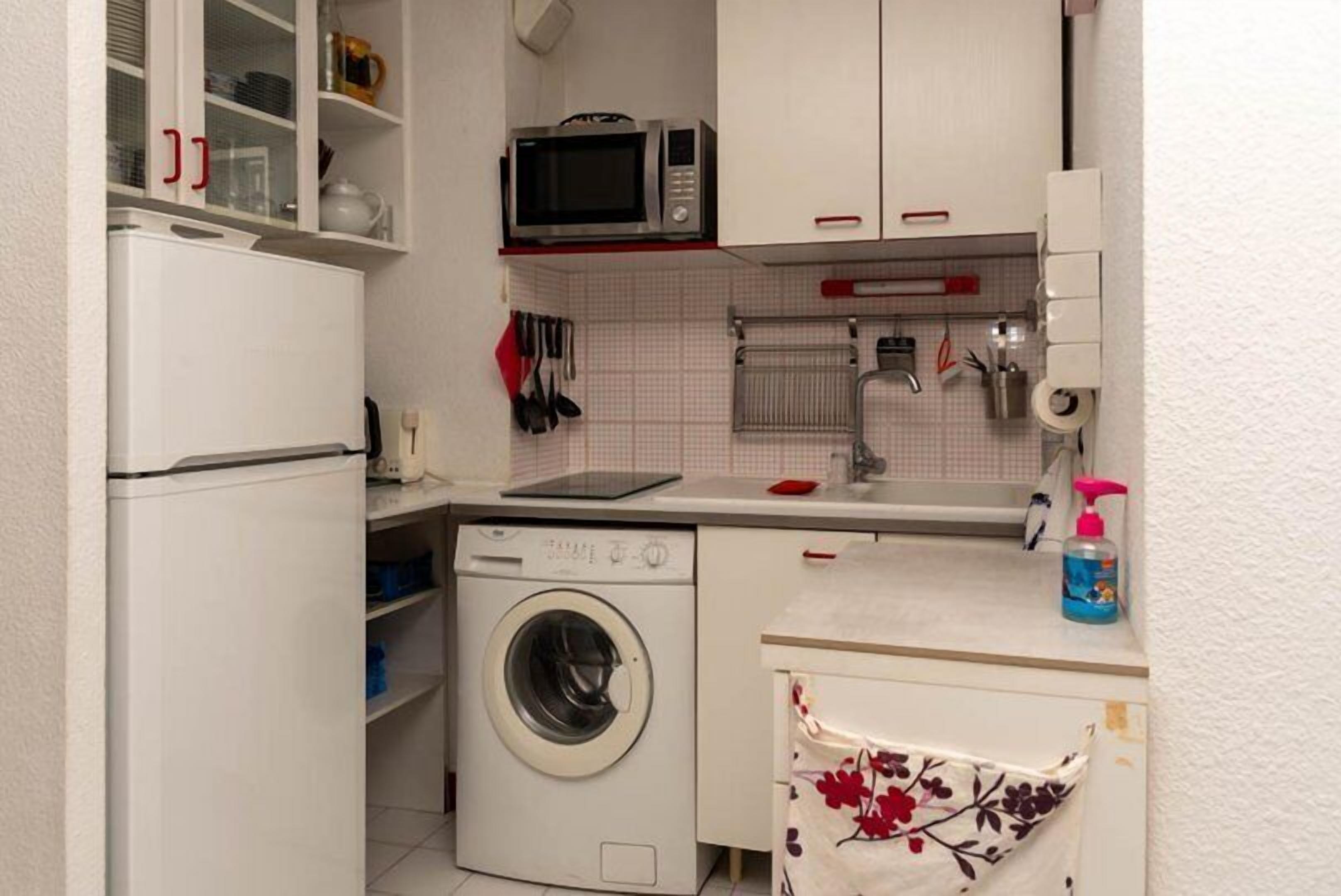 Una cocina compacta con lavadora, microondas y una pequeña encimera.