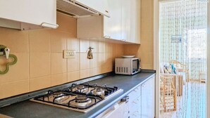 Een keuken met een gasfornuis, een magnetron en kastjes.