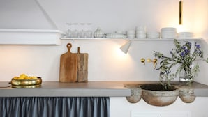 A kitchen counter with a cutting board, a bowl of lemons, a potted plant, and a hanging light fixture. - Villa delle Colline Lucchesi (Lucca)