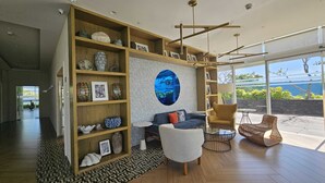 Ein modernes Wohnzimmer mit einem großen Bücherregal aus Holz, einer runden Wanddekoration und Blick ins Freie.