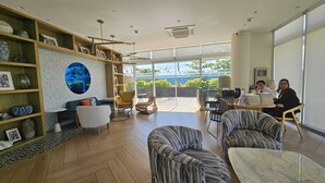 Ein geräumiges Zimmer mit großem Fenster und Aussicht auf eine reizvolle Landschaft, Holzboden und verschiedenen Sitzmöglichkeiten, darunter eine Couch und Stühle.