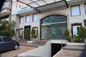 Un hôtel avec une enseigne indiquant « Restaurant Oorja » et « Hôtel SatlaJ » au-dessus de l’entrée.