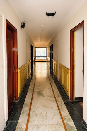 A long, narrow hallway with marble flooring and wooden doors on both sides. - Hotel Satlaj Raipur (Raipur)