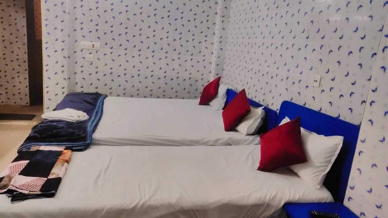 Una habitación con dos camas, cada una con ropa blanca y almohadas rojas, y un cabecero azul.