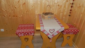 A wooden dining table with a heart-patterned tablecloth and matching benches. A basket with a handle is placed on the table. - CHAMBRE-GÎTE LES TOURTEREAUX EN ISERE (LE VERCORS) (Saint-Just-de-Claix)