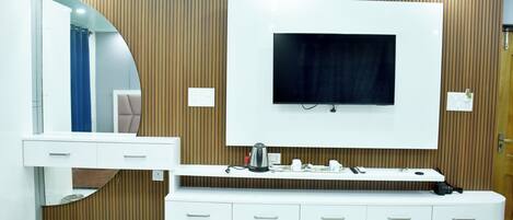 A modern bathroom with a large mirror, a vanity with drawers, a mounted TV, and a wooden panel wall.