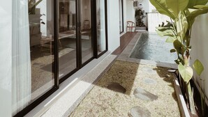 A modern house with large sliding glass doors, a wooden ceiling, and a small pool area with a grassy border. - Villa Indah (Ungasan)