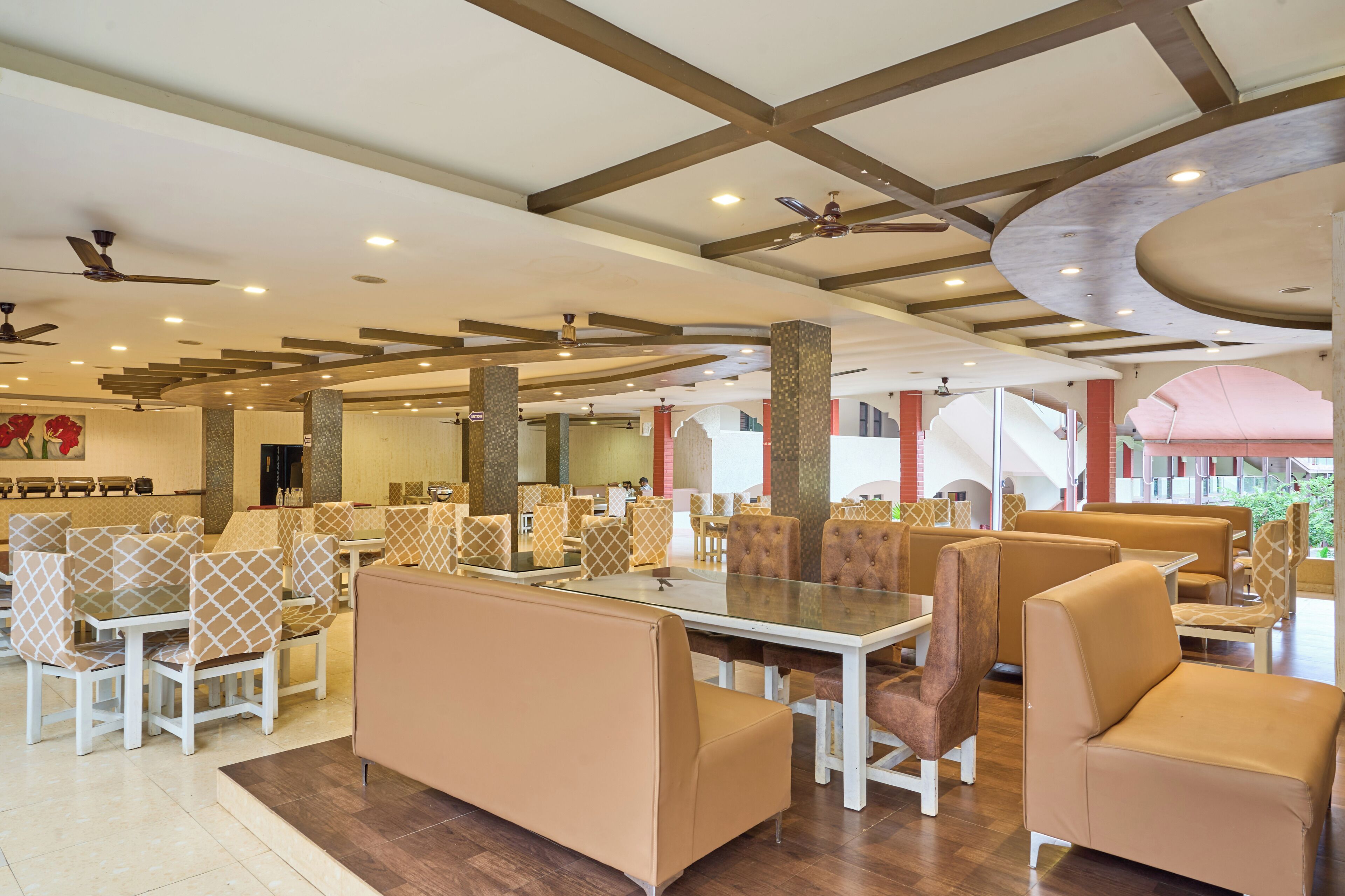 A spacious restaurant with high ceilings, exposed beams, and a variety of seating arrangements including booths and tables.
