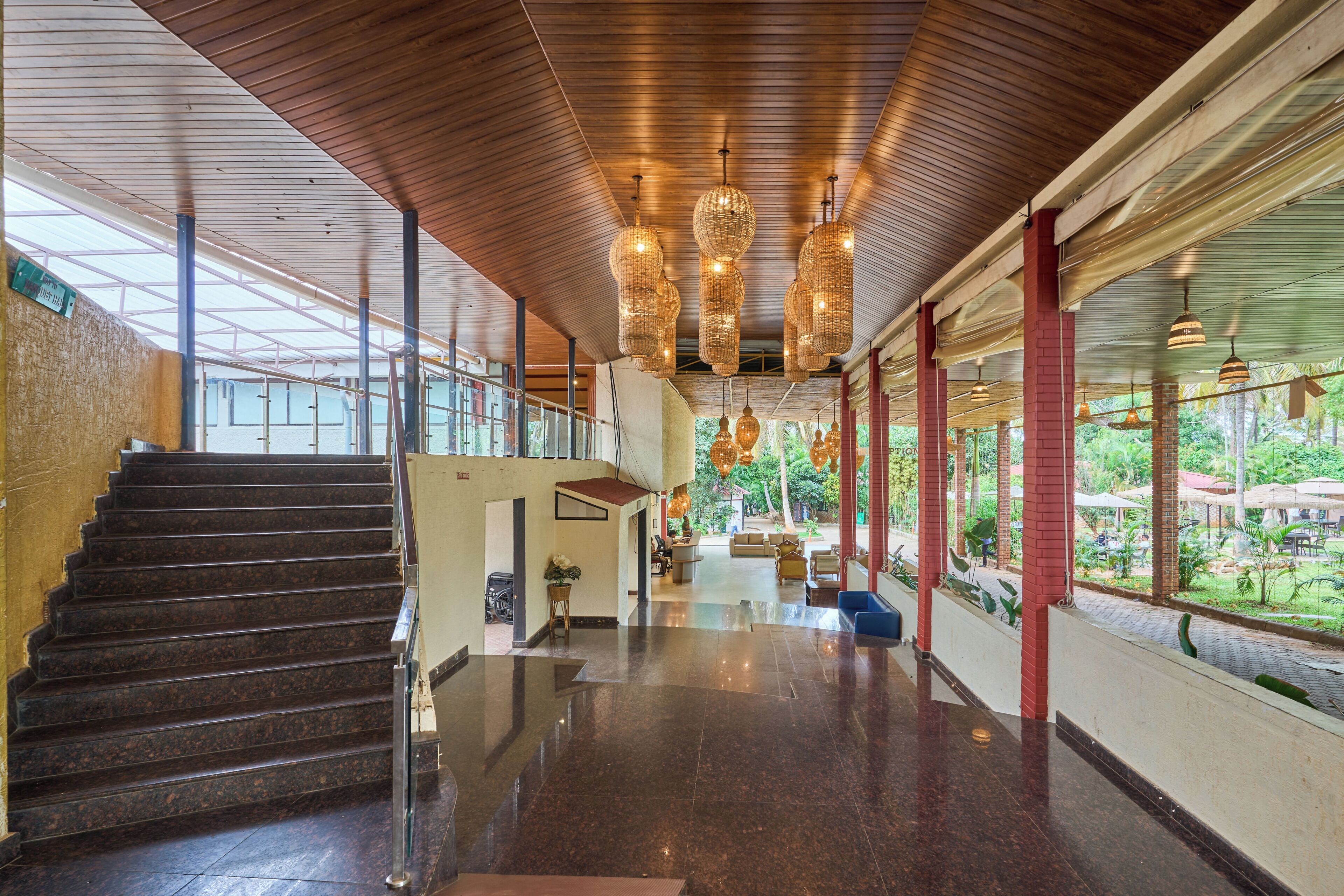 Amplio espacio interior con una escalera que conduce a un nivel superior, una recepción y vistas al exterior.