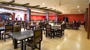 Un restaurant spacieux doté de plusieurs espaces de restauration, de hauts plafonds et de ventilateurs de plafond.