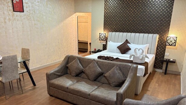Une chambre d’hôtel avec un canapé, un lit avec une tête de lit, une petite table et une chaise.