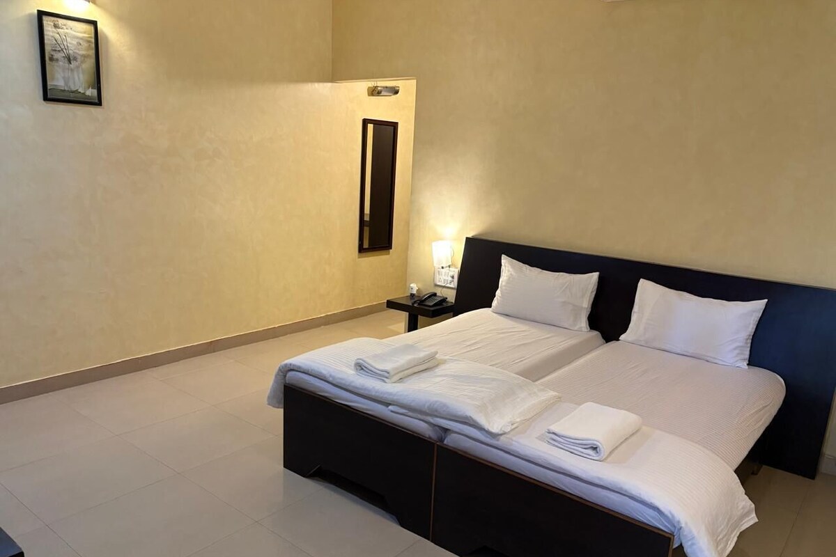 Une chambre d’hôtel avec un grand lit, une table de chevet, une commode et un miroir fixé au mur.
