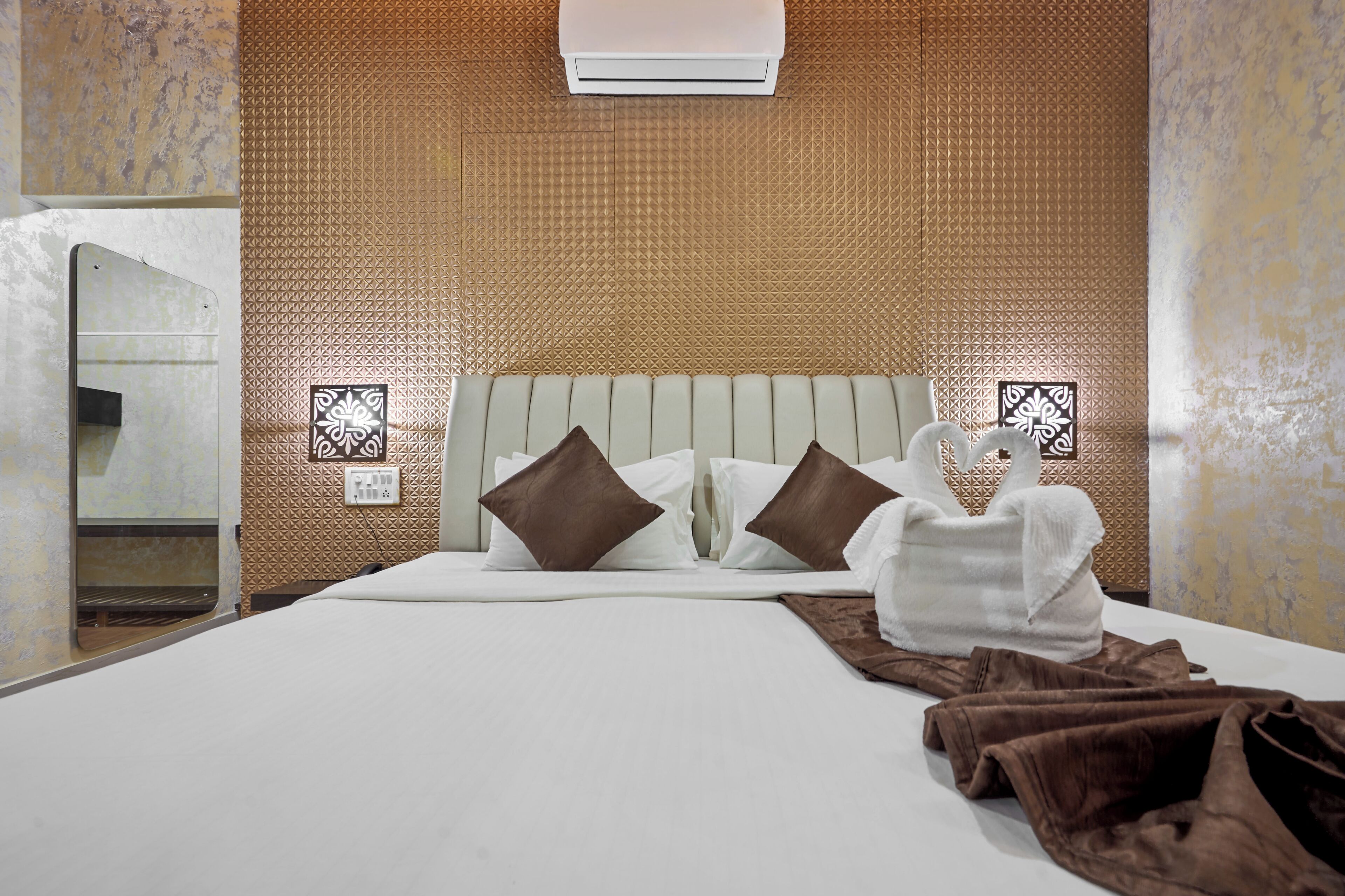 Ett hotellrum med en säng, kuddar, en handduk och en väggmonterad luftkonditioneringsanläggning.