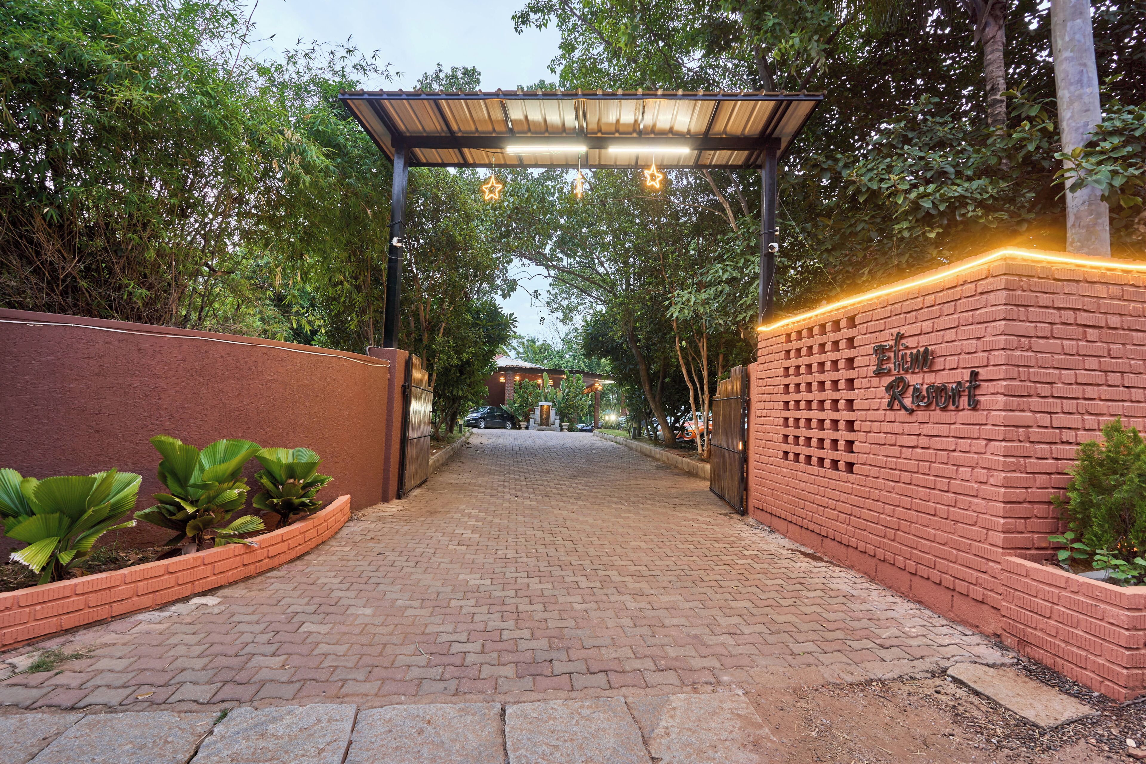 Un camino de ladrillo que lleva a una entrada con puerta y un letrero que dice 'Elim Resort'.