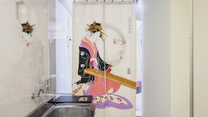 Ein traditioneller japanischer Raum mit einer verschiebbaren Shoji-Schirmwand, die eine historische Persönlichkeit zeigt, einem modernen Waschbecken und einem Holzboden.