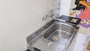 Ein Spülbecken aus Edelstahl mit modernem Wasserhahn, integriertem Mülleimer und einer gefliesten Spritzschutzwand.