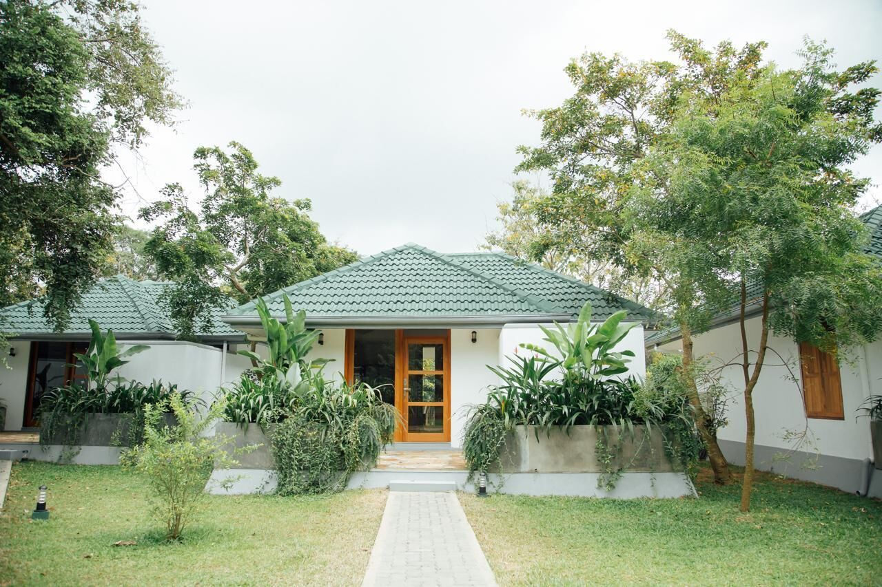 A house with a tiled roof, a wooden door, and a paved entrance.