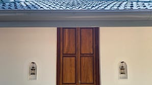 A wooden door with a white wall and two wall-mounted lanterns. - vainika wild (dambulla, matale)