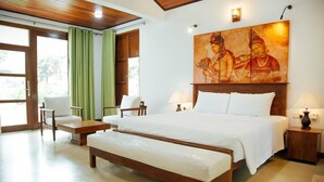 A bedroom with a large bed, two bedside tables, a bench, a chair, and a painting on the wall. - vainika wild (dambulla, matale)