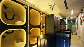 A hotel room with a unique design featuring large, smiley-faced windows and a small bed. - ACE Hostel  (Hanoi)