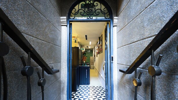 A hallway with a black and white checkered floor, a decorative archway, and a staircase with metal railings. - ACE Hostel  (Hanoi)