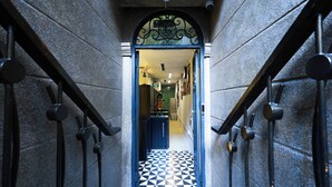A narrow hallway with a black and white checkered floor, leading to a room with a blue door and a decorative archway. - ACE Hostel  (Hanoi)
