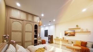 A modern bedroom with a large bed, a wooden wardrobe, a desk, and a sofa. - NomadStay Coastline Living (Da Nang)