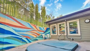 Un murale colorato, una piccola piscina con trampolino e un edificio con finestre e una torre dell'orologio.