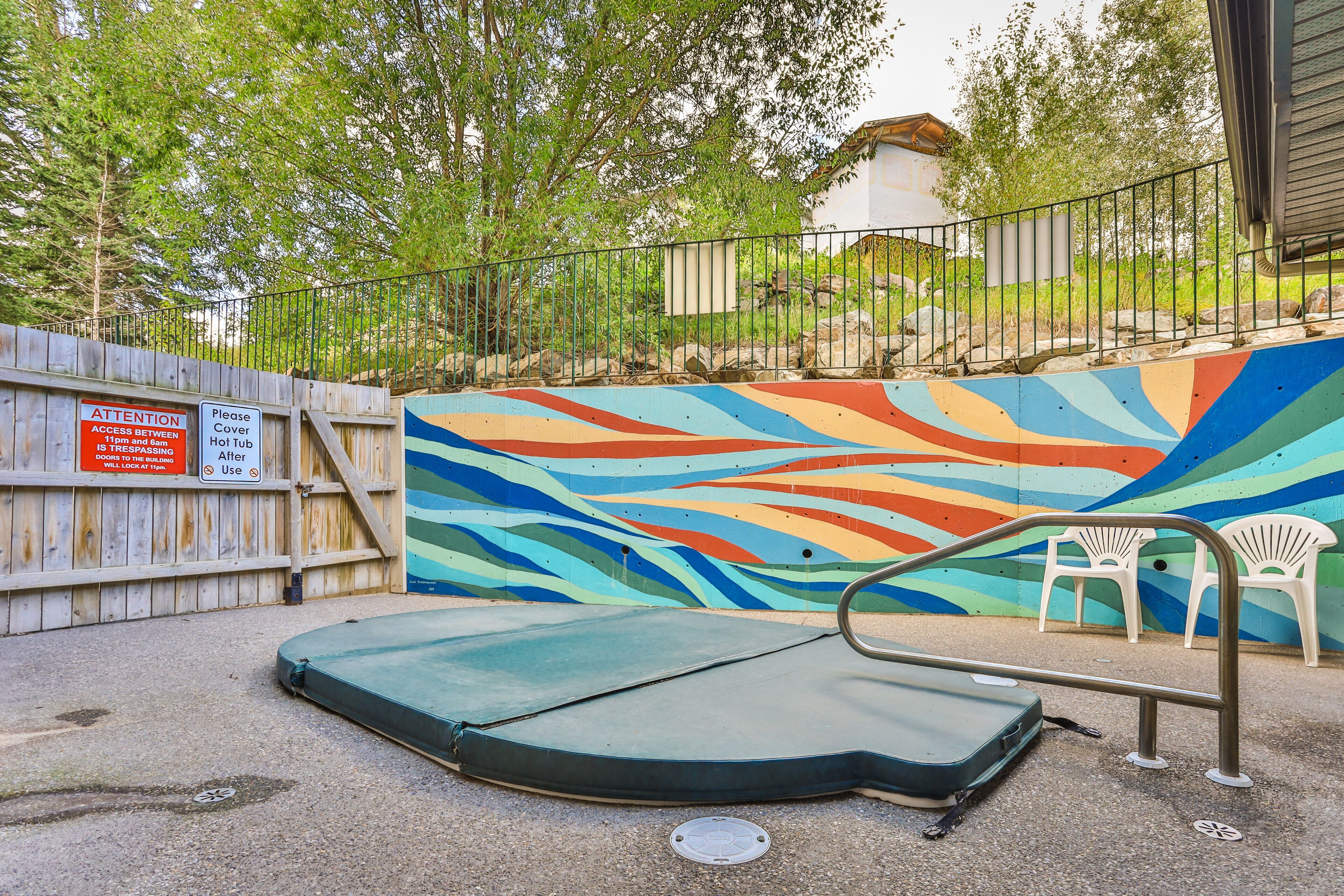 A colorful mural, a metal bench, and a covered area with a metal railing.