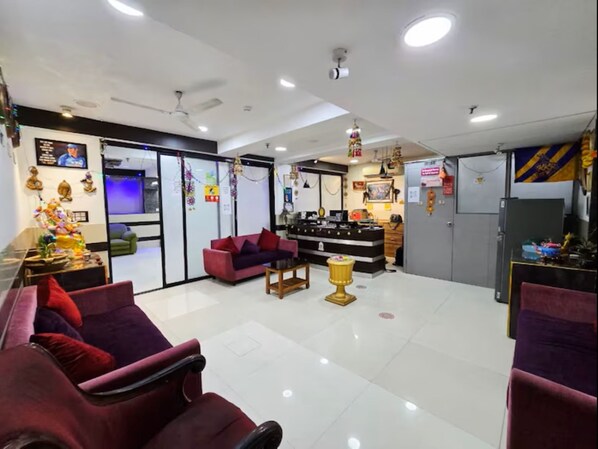 A spacious living area with a red sofa, a small table, and a decorative lamp. - The Platinum saltlake (Bidhannagar)
