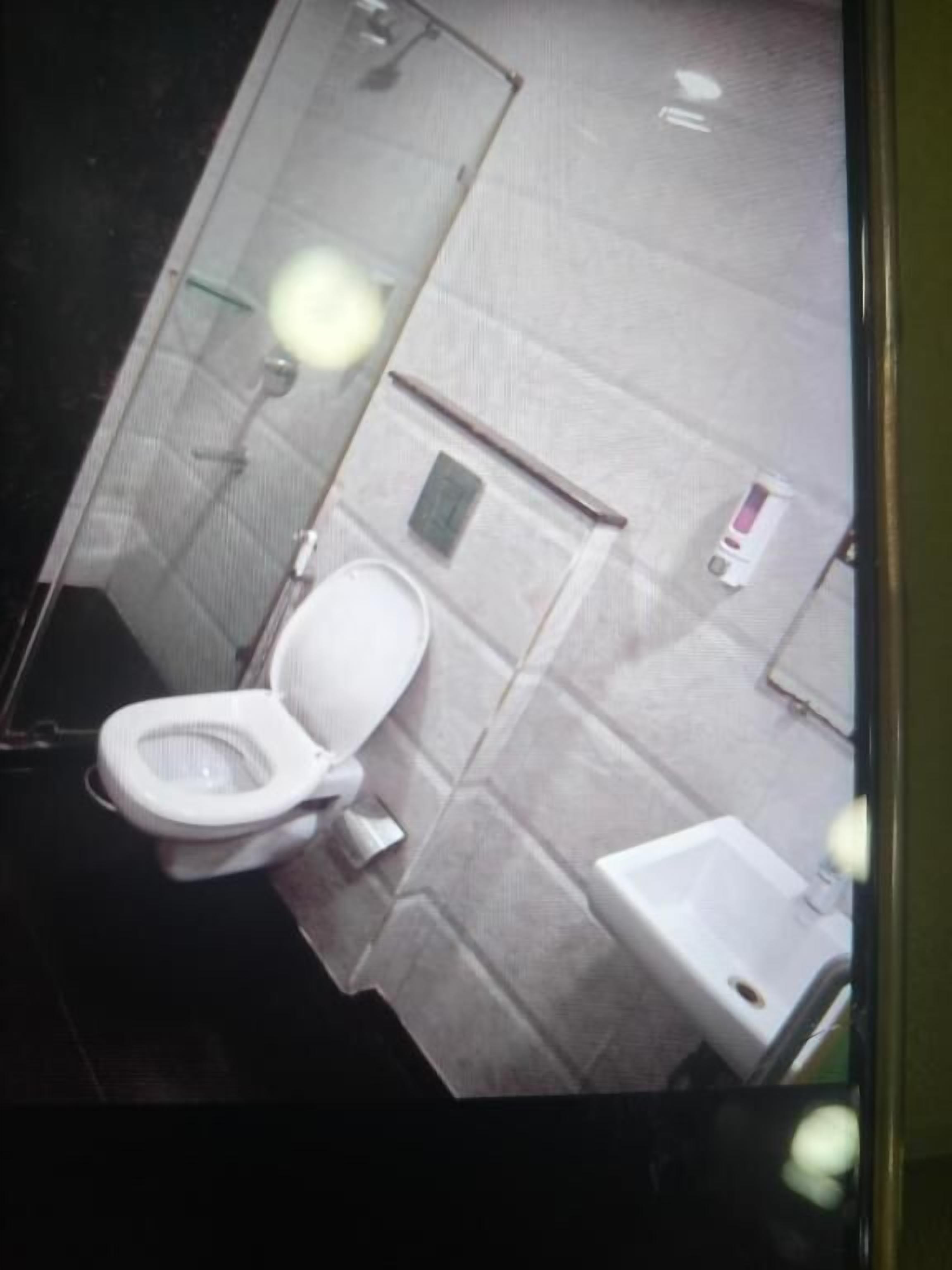 Een badkamer met toilet, wastafel en spiegel.