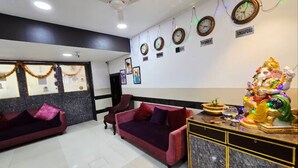 A hotel lobby with two sofas, a ceiling fan, wall clocks, and a statue. - The Platinum saltlake (Bidhannagar)