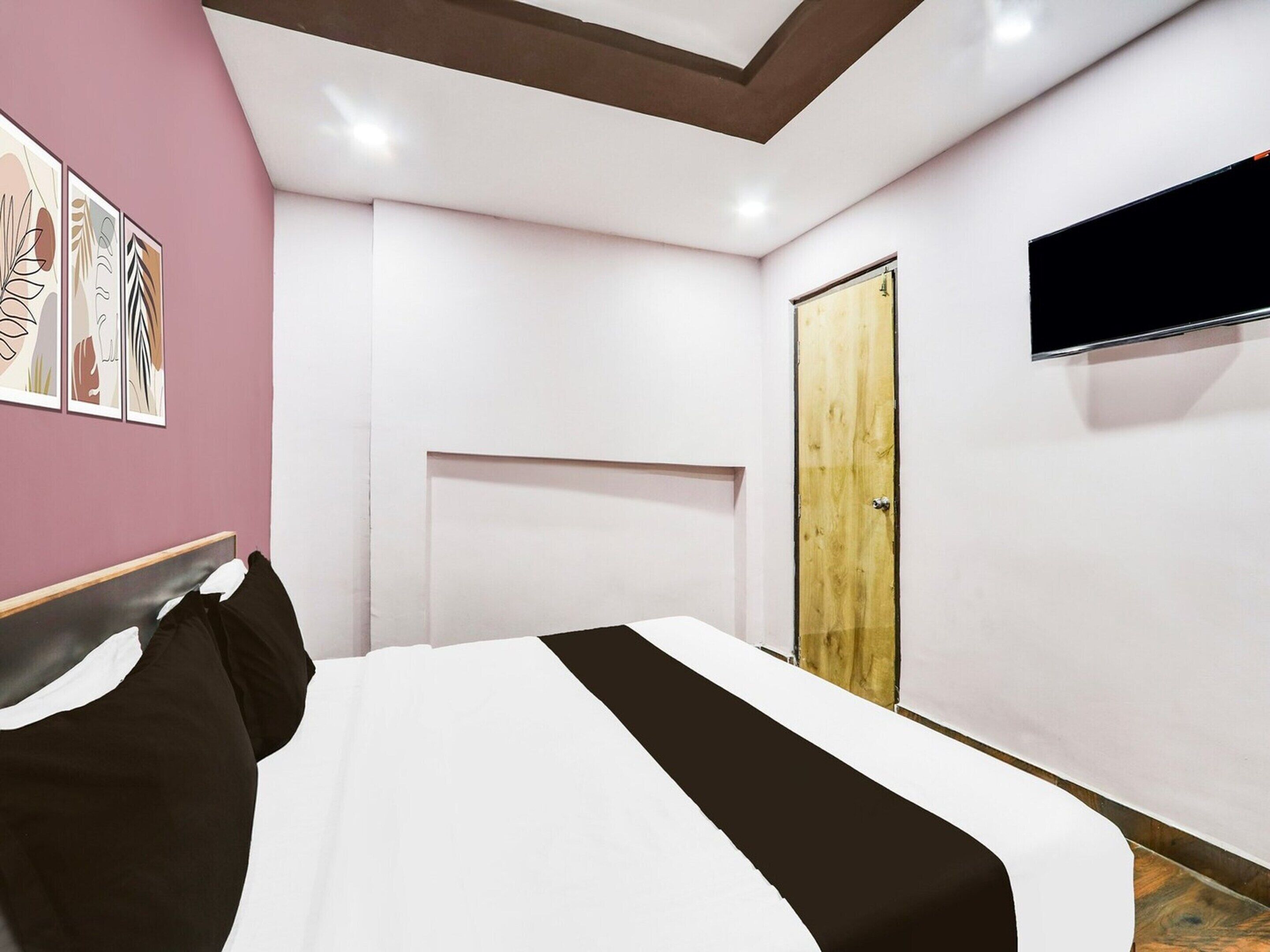 A bedroom with a bed, a wooden door, and a TV mounted on the wall.