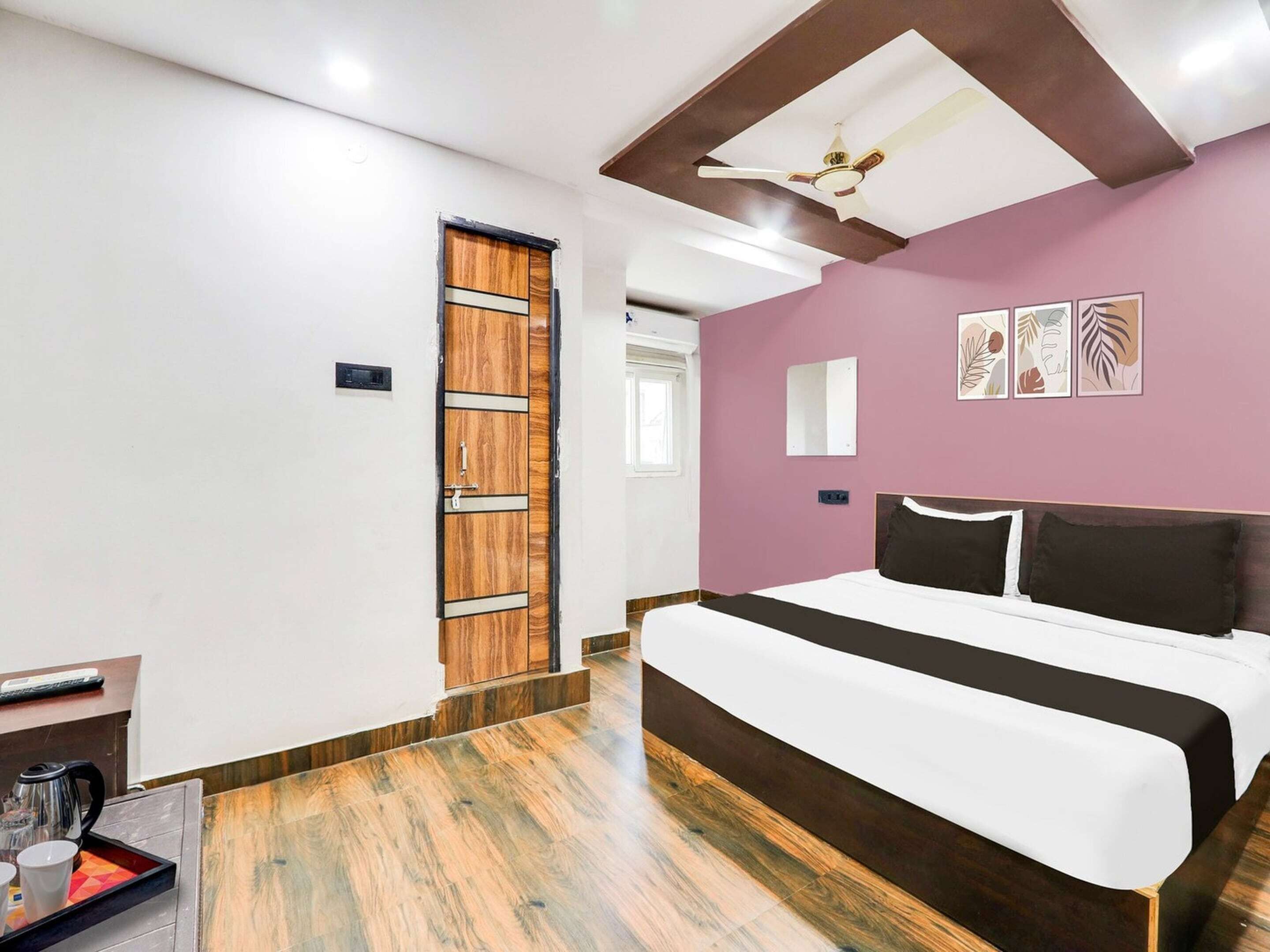 Una habitación de hotel moderna con una cama grande, suelo de madera, ventilador de techo y una puerta de diseño único.