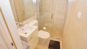 Une salle de bain avec une douche à parois de verre, un lavabo blanc et des toilettes.